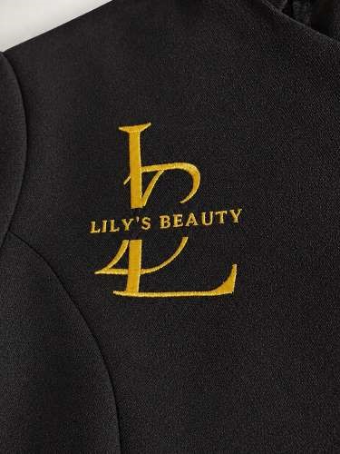 Beautician tunic – A customised black beauty salon tunic featuring elegant gold embroidered branding with the “Lily’s Beauty” logo on the chest, carefully finished with refined detailing, smooth fabric texture, and a professional luxury appearance.
