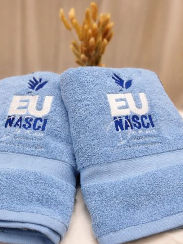 Embroidered towels – A pair of customised light blue towels featuring “EU NASCI” embroidery, carefully crafted with soft texture and enhanced colour detail.